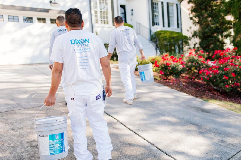 Dixon Painting, experts in Atlanta, GA, carrying paint cans into a client's driveway