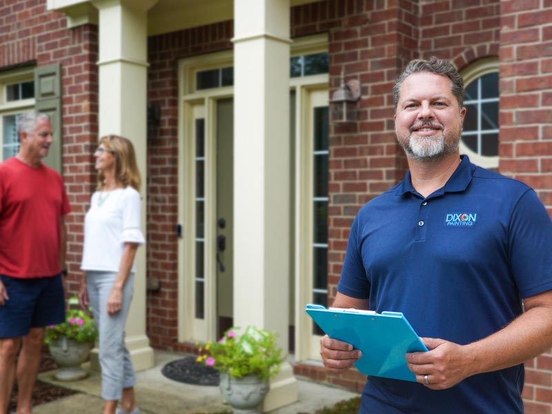 A Dixon Painting expert in Marietta, GA, is standing outside a house while a couple is talking