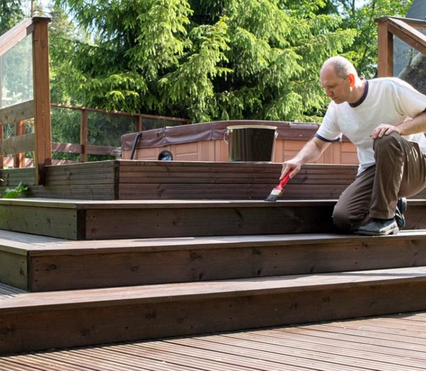 A man diligently painting a wooden deck as part of Dixon Painting's services in Atlanta, GA