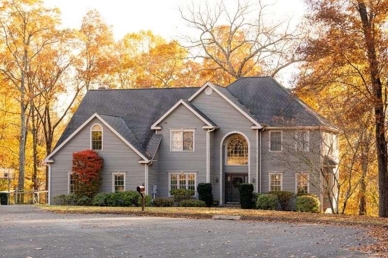 Gray two-story home after painting service in Atlanta and Roswell, GA, surrounded by fall trees