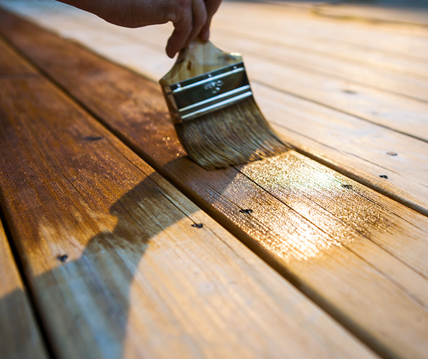 A man diligently painting a wooden deck as part of Dixon Painting's services in Atlanta, GA
