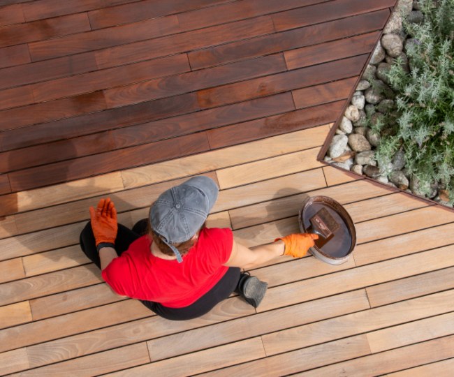 Painter staining a wooden deck- Dixon Painting